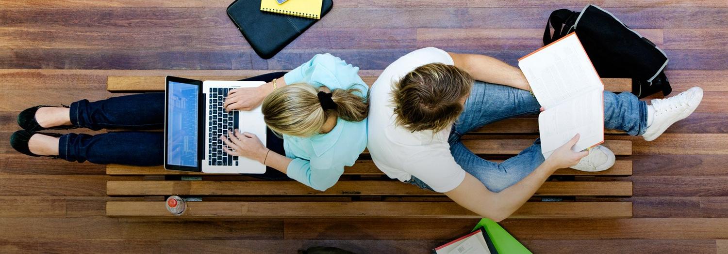 Male and Female students seated back to back while working on computers